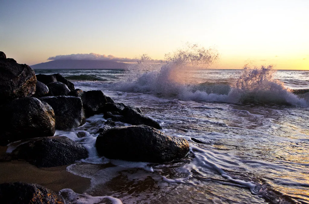 Waves breaking on a rocky Hawaiian shore at sunset