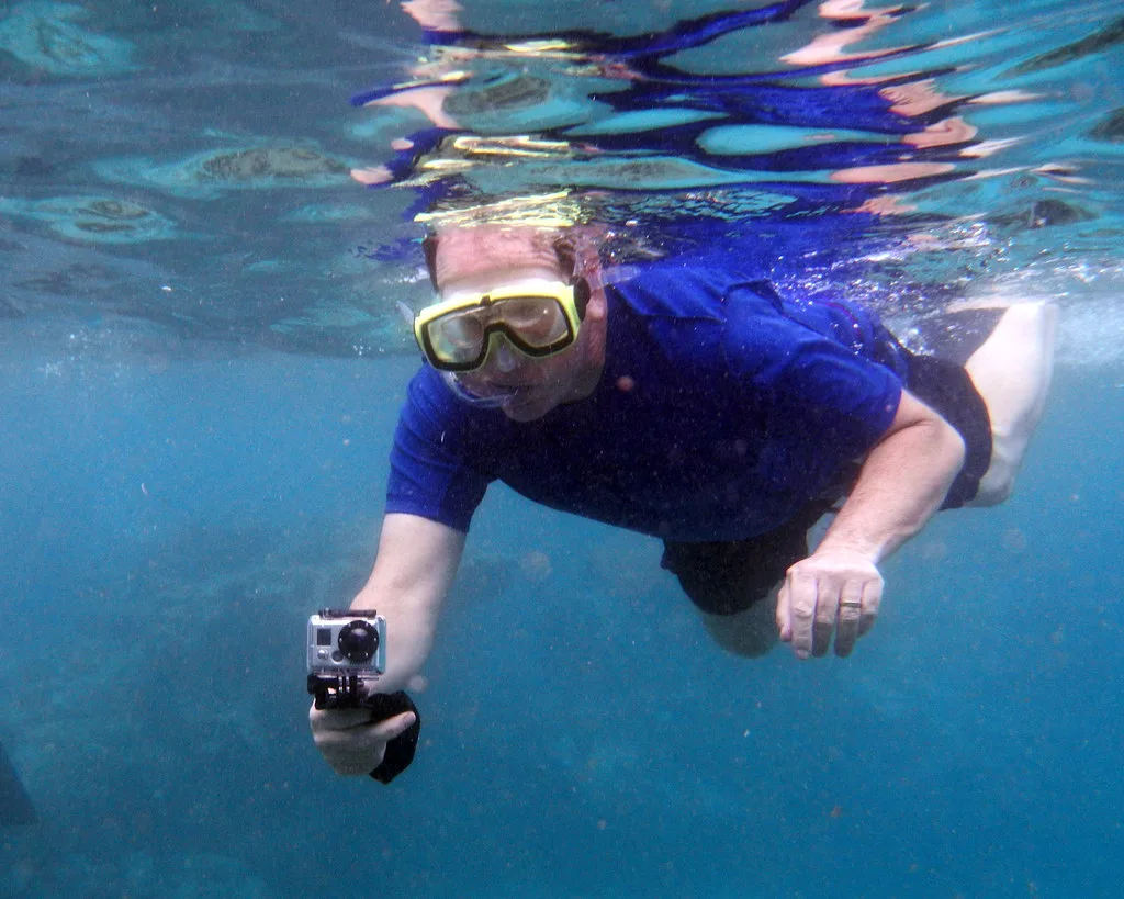 Snorkeler with a camera over a sandy bottom