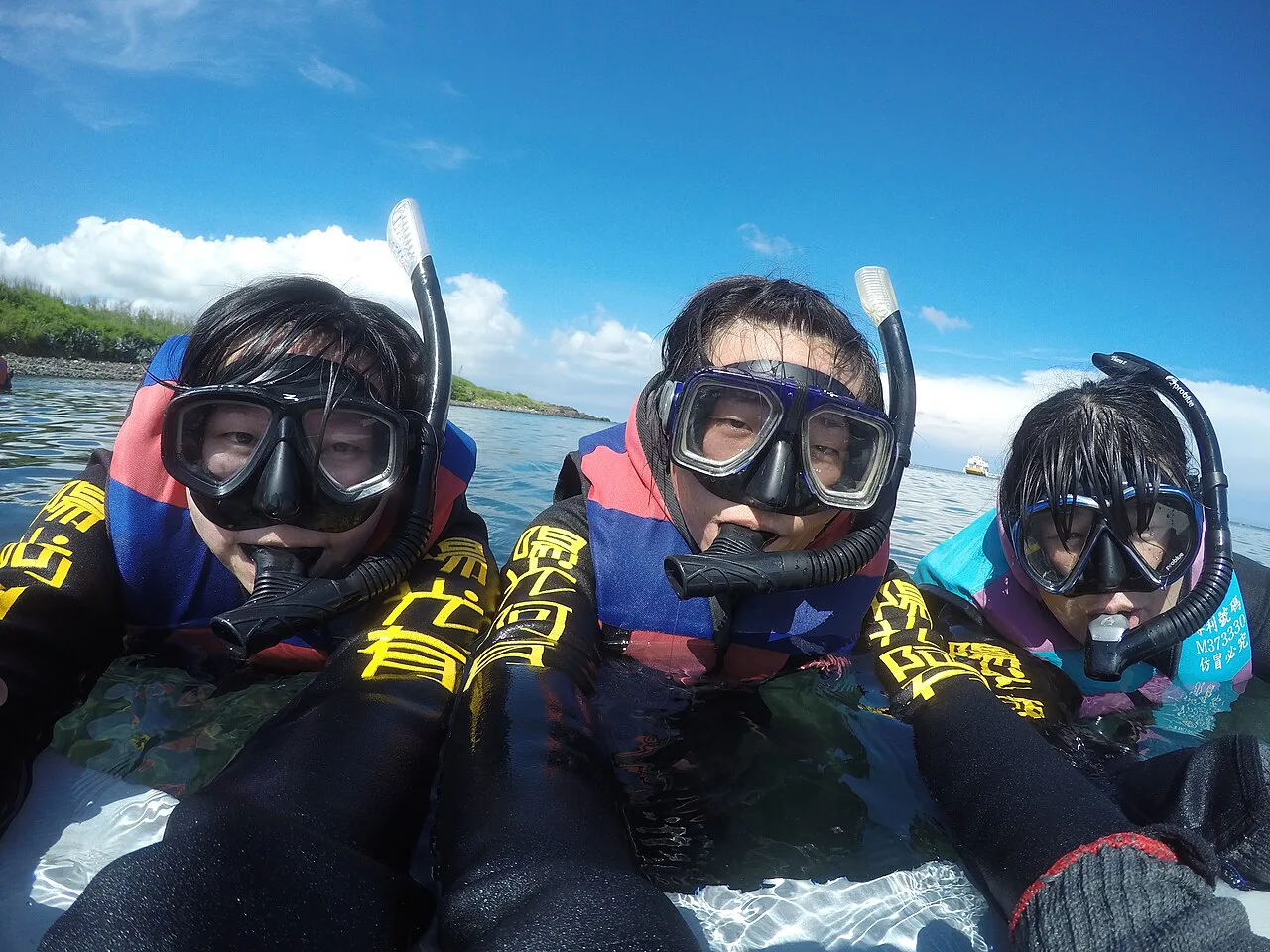 Three snorkelers in masks and wetsuits