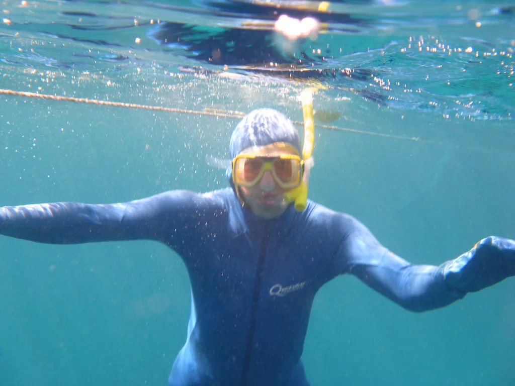Snorkeler in a wetsuit biting on the snorkel mouthpiece